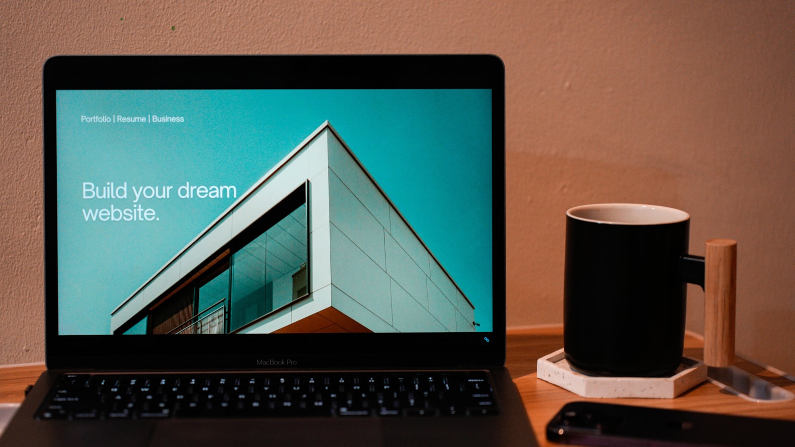 A laptop on a desk displaying a website hero section that reads "Build your dream website"