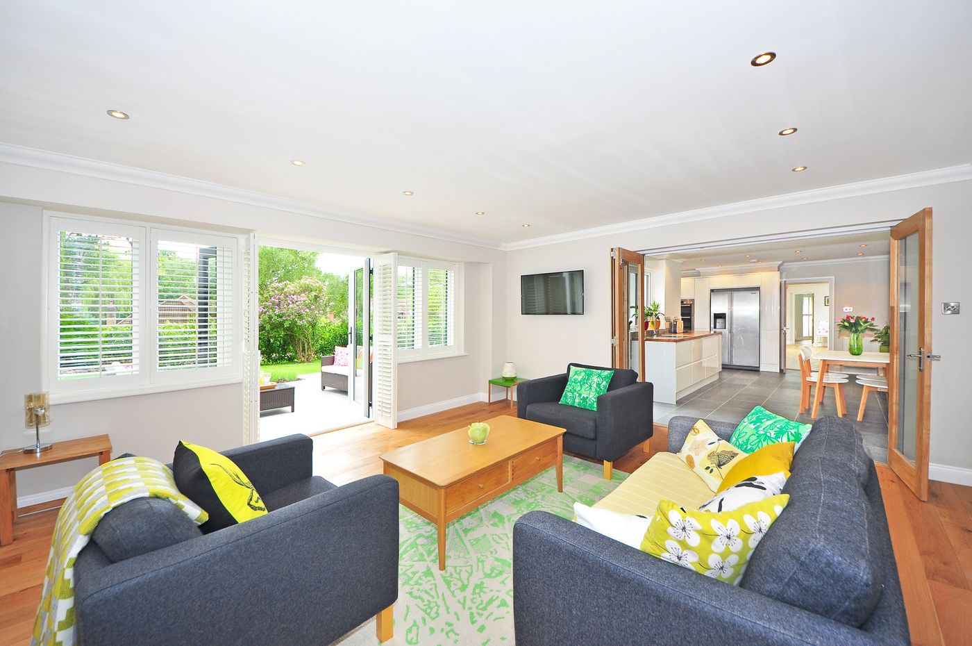 An open-plan living room opening onto a garden through folding doors.
