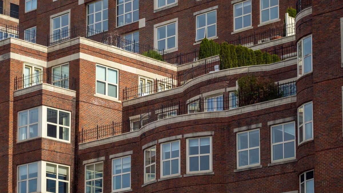 A red brick apartment building with stepped terraces and railings.